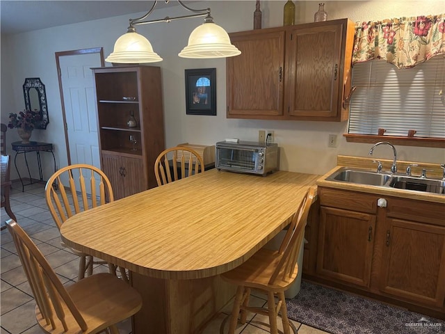 kitchen featuring a kitchen bar, sink, light tile patterned floors, and hanging light fixtures