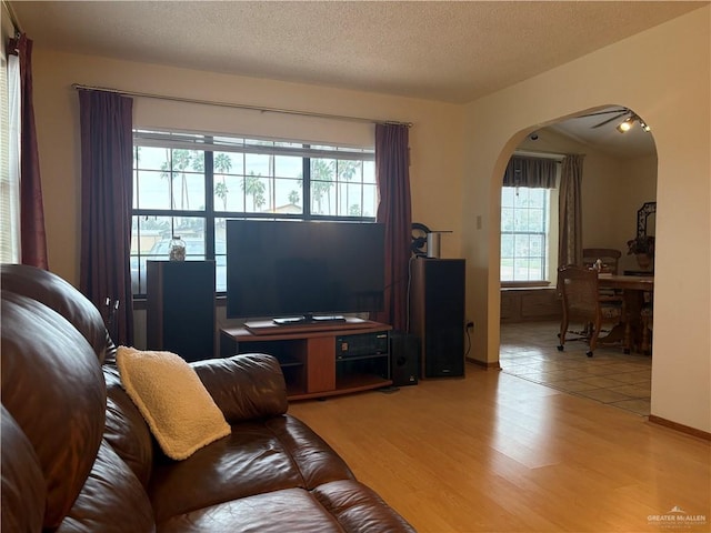 living room featuring a textured ceiling, light hardwood / wood-style flooring, and ceiling fan