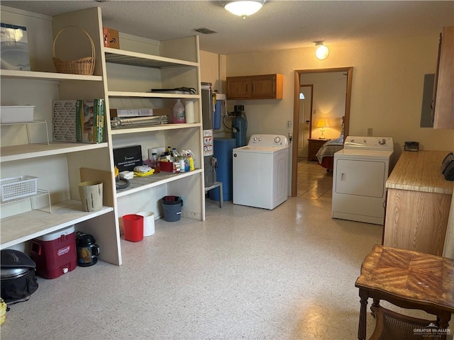 laundry area with cabinets, a textured ceiling, electric panel, and washing machine and clothes dryer