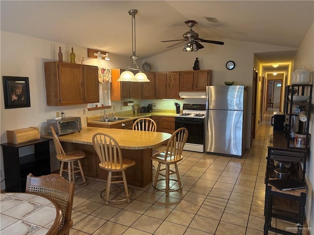 kitchen featuring kitchen peninsula, white gas range oven, vaulted ceiling, sink, and stainless steel refrigerator