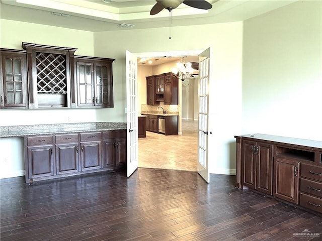 interior space with dark wood-type flooring, sink, hanging light fixtures, stainless steel dishwasher, and dark brown cabinetry