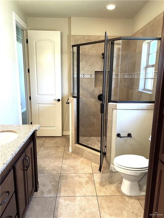 bathroom with tile patterned flooring, vanity, toilet, and an enclosed shower