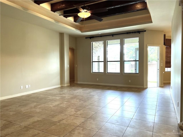 spare room featuring beamed ceiling, light tile patterned floors, a tray ceiling, and ceiling fan