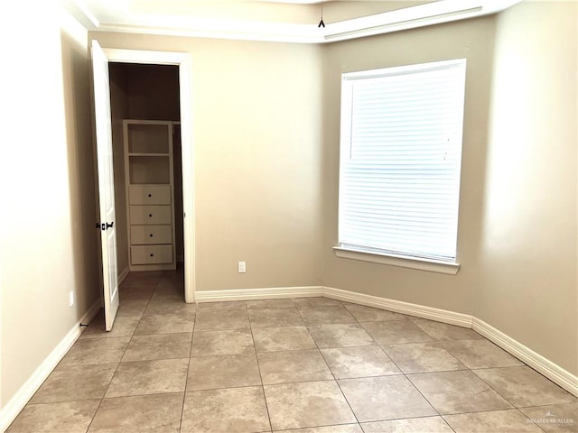 unfurnished bedroom featuring light tile patterned floors and a walk in closet