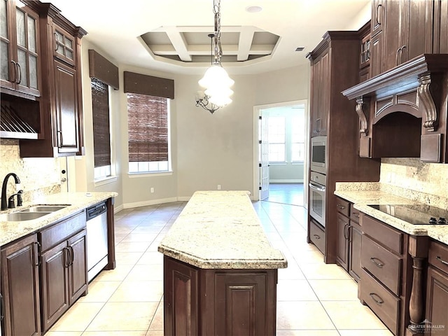 kitchen featuring pendant lighting, sink, appliances with stainless steel finishes, a tray ceiling, and a kitchen island