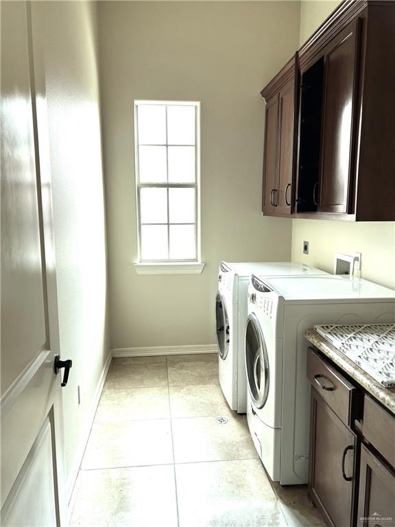 washroom featuring washing machine and clothes dryer, light tile patterned flooring, and cabinets