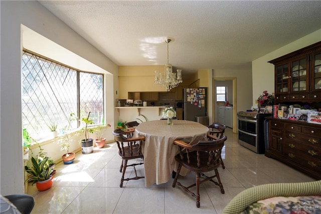 603 S Alamo Rd, Alamo, TX 78516 - dining room with light tile patterned floors, washer / clothes dryer, a textured ceiling, and a notable chandelier