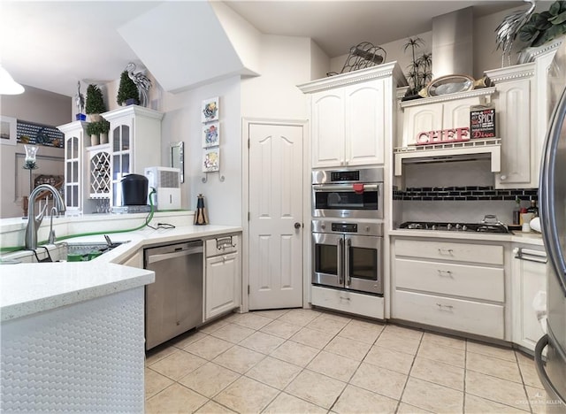 kitchen featuring appliances with stainless steel finishes, white cabinetry, light tile patterned floors, and sink