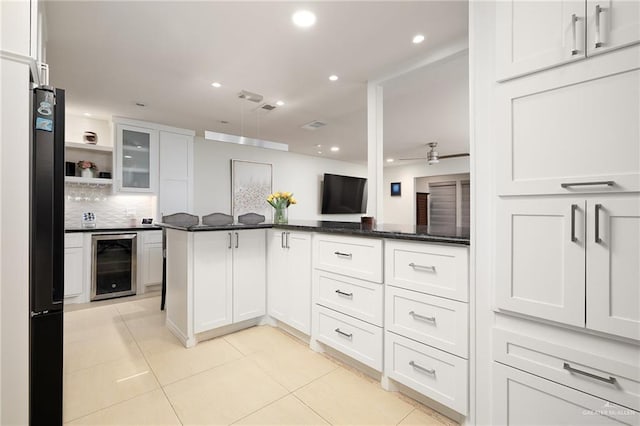 kitchen featuring light tile patterned floors, ceiling fan, backsplash, white cabinets, and beverage cooler