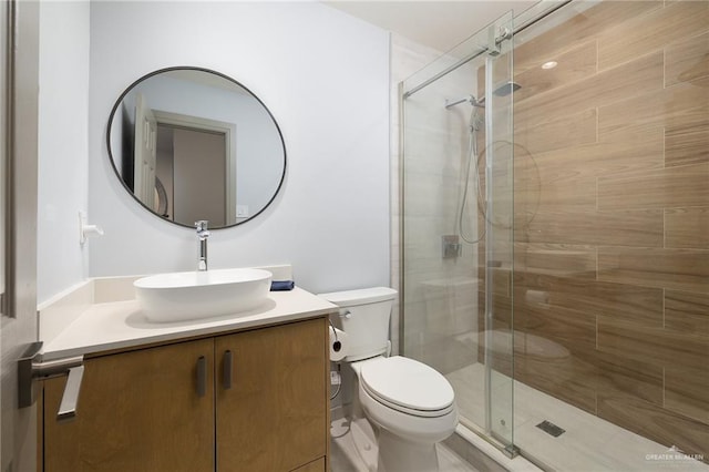 bathroom featuring vanity, a shower with door, and toilet