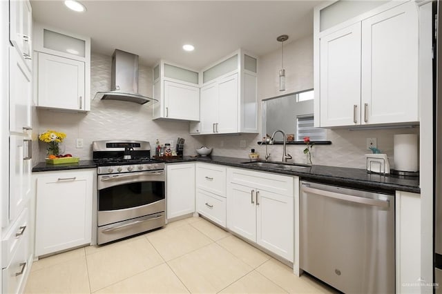 kitchen with stainless steel appliances, white cabinetry, sink, and wall chimney range hood