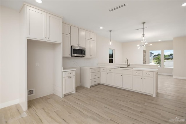 2510 E Solar Dr, Mission, TX 78574 - kitchen featuring stainless steel microwave, light wood-style floors, a peninsula, recessed lighting, and hanging light fixtures