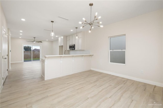 2510 E Solar Dr, Mission, TX 78574 - kitchen featuring stainless steel microwave, white cabinets, light wood-style flooring, light countertops, and recessed lighting