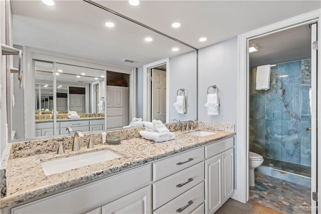 full bathroom featuring toilet, a sink, double vanity, and a stall shower