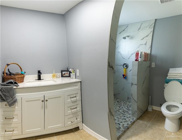 bathroom featuring tiled shower, vanity, toilet, and tile patterned flooring