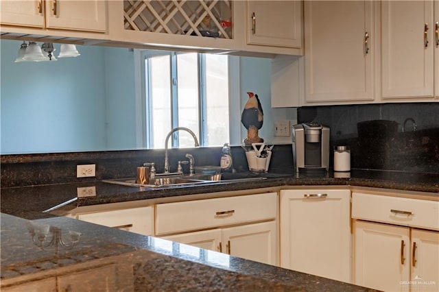 kitchen featuring backsplash, white cabinets, dark stone countertops, and sink