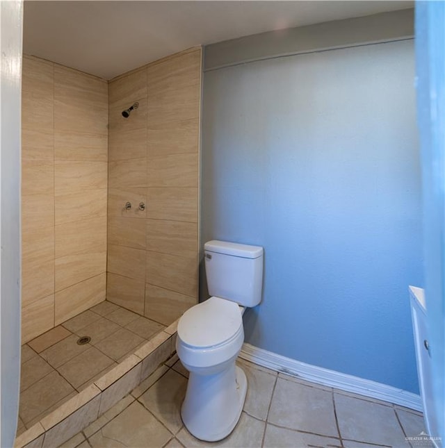 bathroom with tile patterned floors, tiled shower, and toilet