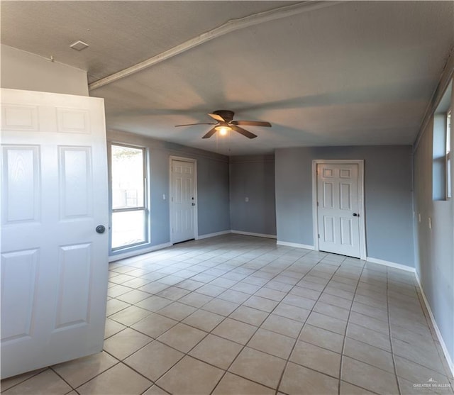 tiled empty room featuring vaulted ceiling and ceiling fan