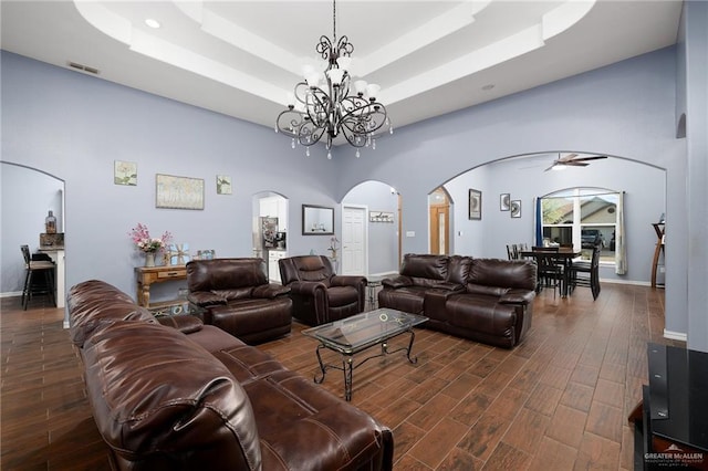 living room with visible vents, dark wood finished floors, a raised ceiling, arched walkways, and a high ceiling