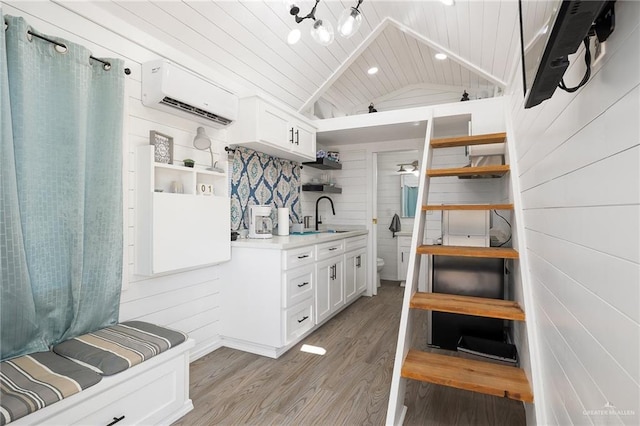 mudroom with lofted ceiling, wood ceiling, a wall mounted air conditioner, light wood-type flooring, and a sink