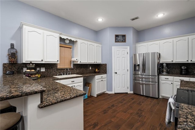 kitchen featuring stainless steel appliances, a peninsula, a sink, visible vents, and white cabinets