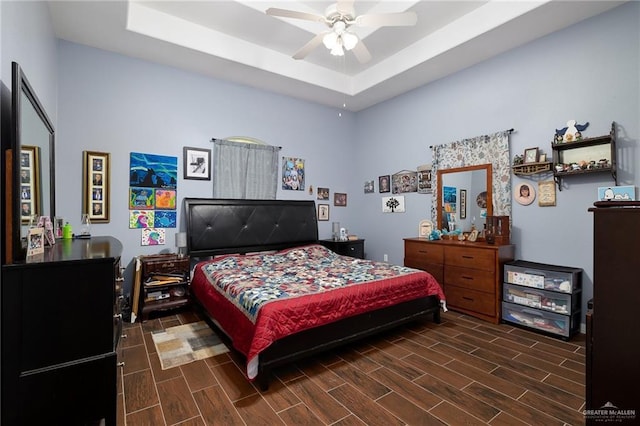 bedroom featuring ceiling fan, a tray ceiling, and wood finish floors