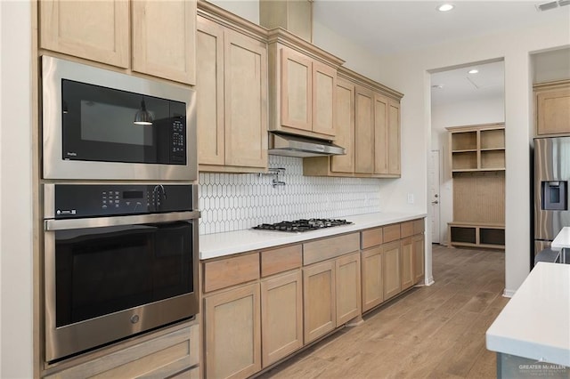 kitchen with light hardwood / wood-style floors, light brown cabinetry, stainless steel appliances, and extractor fan