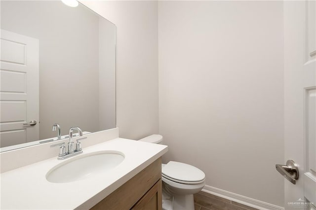 bathroom with hardwood / wood-style floors, vanity, and toilet