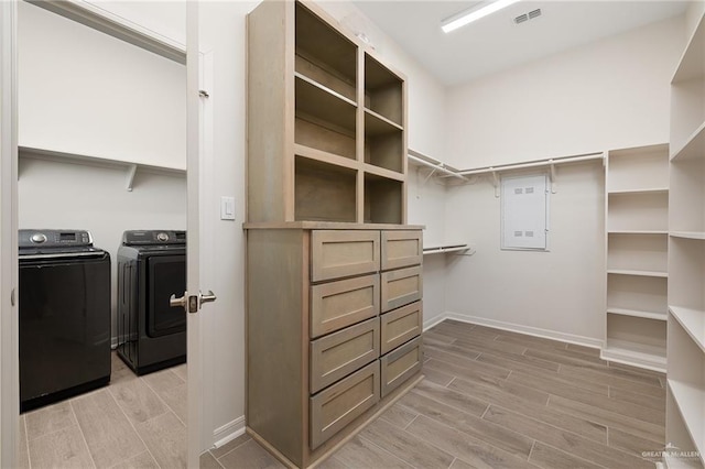 walk in closet with washer and dryer and light hardwood / wood-style floors