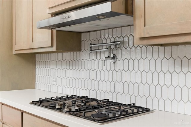 kitchen featuring ventilation hood, light brown cabinets, backsplash, and gas cooktop