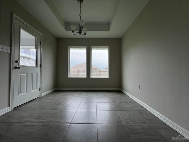 unfurnished room featuring a raised ceiling and a notable chandelier