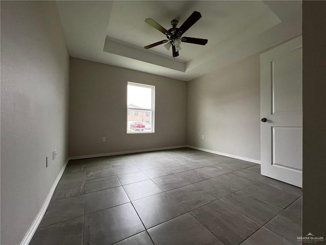 unfurnished room with ceiling fan and a raised ceiling