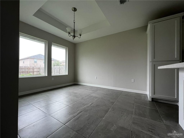 unfurnished room with a raised ceiling and an inviting chandelier