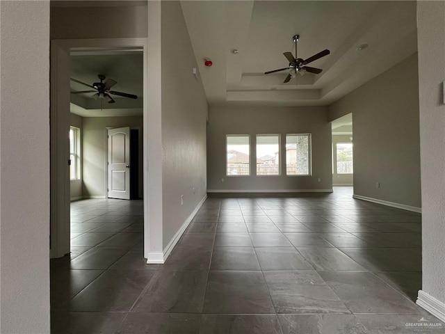 tiled spare room with a raised ceiling and ceiling fan