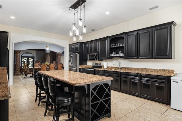 kitchen featuring stainless steel appliances, a center island, pendant lighting, and light stone counters