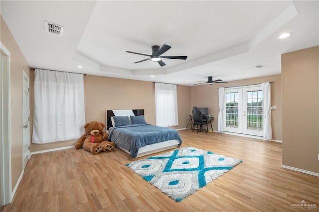 bedroom featuring hardwood / wood-style floors, a raised ceiling, ceiling fan, french doors, and access to outside