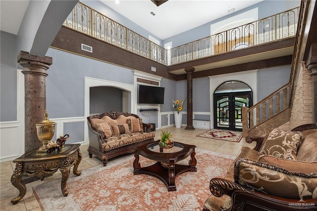 tiled living room featuring ornate columns, french doors, and a high ceiling