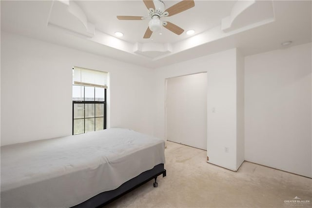 bedroom featuring ceiling fan, light carpet, and a tray ceiling