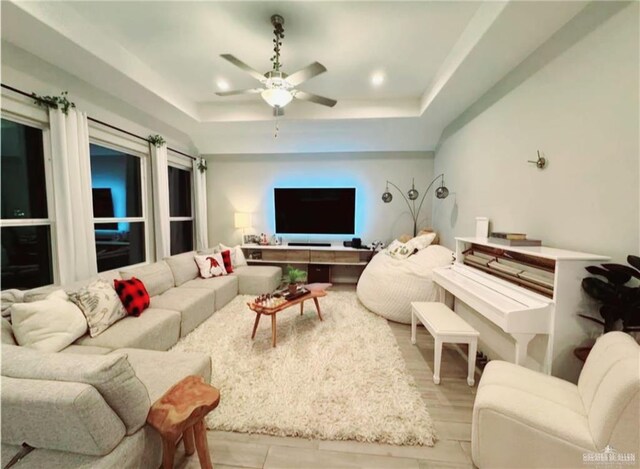 living room with ceiling fan and a raised ceiling