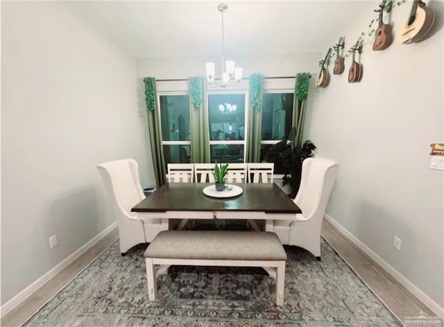 dining room with baseboards, wood finished floors, and an inviting chandelier