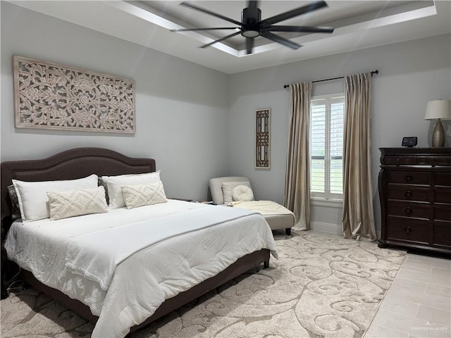 tiled bedroom featuring a raised ceiling and ceiling fan