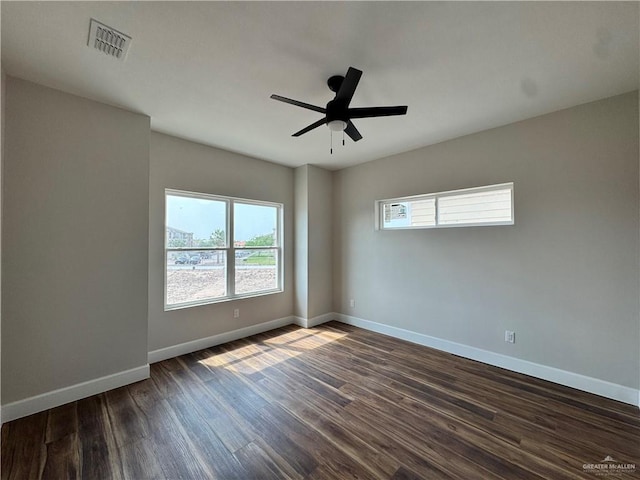 empty room with dark wood finished floors, baseboards, ceiling fan, and visible vents