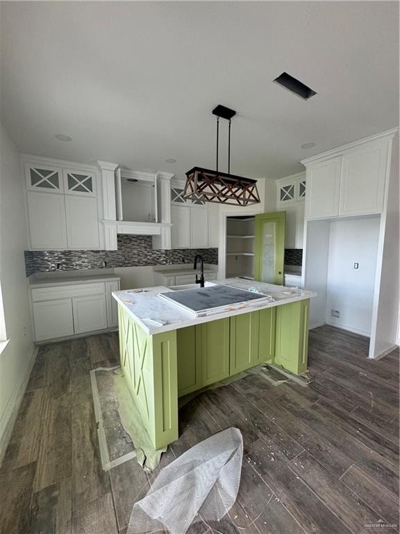 kitchen featuring hanging light fixtures, white cabinetry, a kitchen island with sink, and dark wood-type flooring