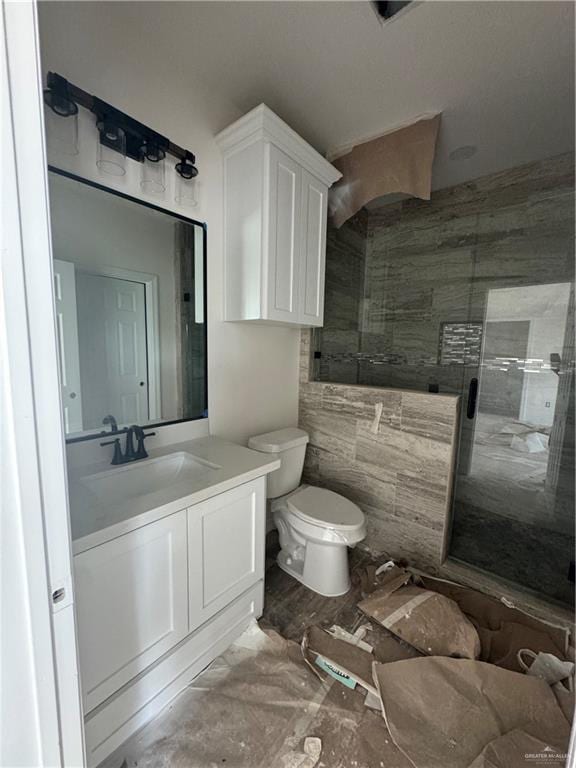 bathroom with vanity, toilet, walk in shower, and tile walls