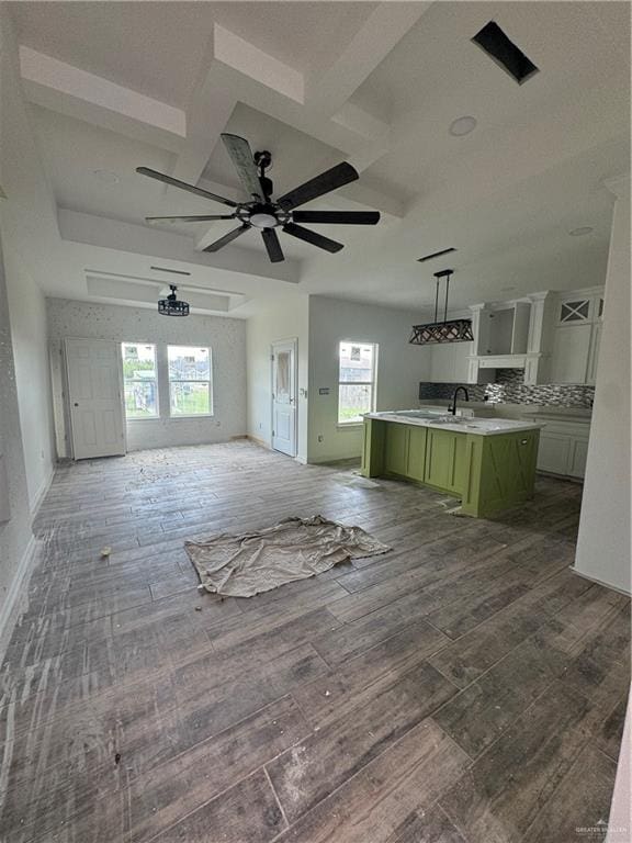 unfurnished living room with ceiling fan, a healthy amount of sunlight, and dark wood-type flooring