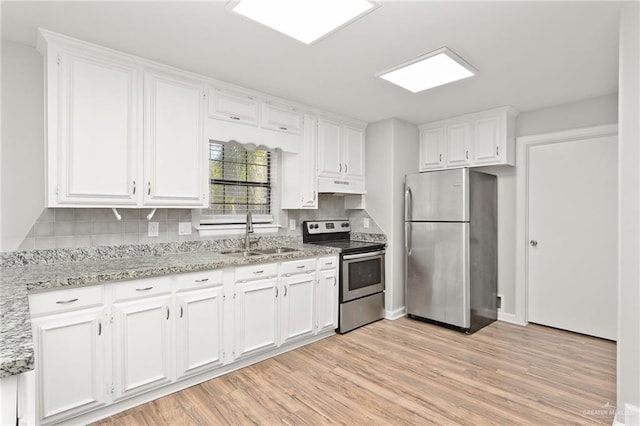 kitchen with light stone countertops, white cabinetry, sink, light hardwood / wood-style floors, and appliances with stainless steel finishes