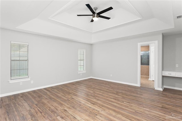 spare room with wood-type flooring, a tray ceiling, and ceiling fan