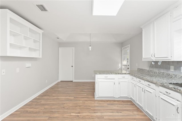 kitchen featuring kitchen peninsula, light hardwood / wood-style flooring, decorative backsplash, light stone countertops, and white cabinetry