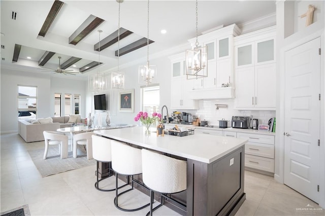 1306 E Danielle Ave, Pharr, TX 78577 - kitchen featuring decorative backsplash, light countertops, beam ceiling, a center island with sink, and white cabinetry