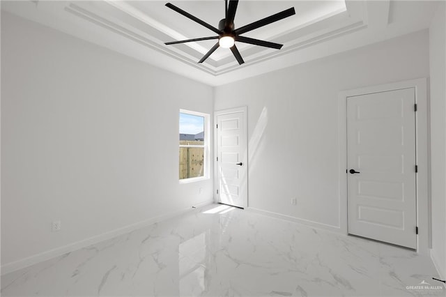 spare room featuring a raised ceiling and ceiling fan